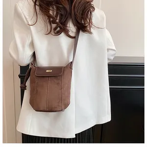 Detail of brown bucket bag featuring suede leather patchwork and a gold metal buckle