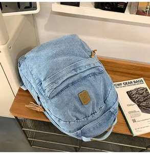 Detail of light blue washed denim backpack with leather patch on a wooden desk
