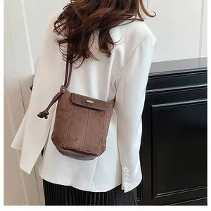 Detailed view of deep brown bucket bag with leather patchwork on model in white blazer