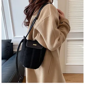 Detail of black bucket bag featuring white contrast stitching and gold metal buckle hardware