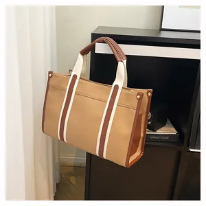 Detail der khakifarbenen Canvas-Tasche mit braunem Lederbesatz und Metallnieten