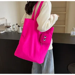 Grand sac fourre-tout rose néon avec pendentif brodé présenté dans un café chic