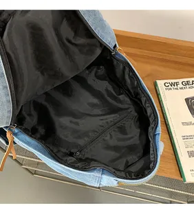 Interior view of denim backpack showing large capacity main pocket and zipper pocket
