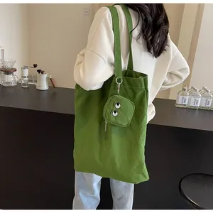 Détail d'un sac cabas en toile verte avec un petit porte-monnaie assorti à motif œil