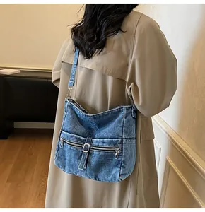 Detail of washed denim crossbody bag with side zipper pockets and adjustable strap