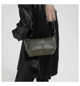 Olive green vintage textured faux leather dumpling bag shown on shoulder of a model