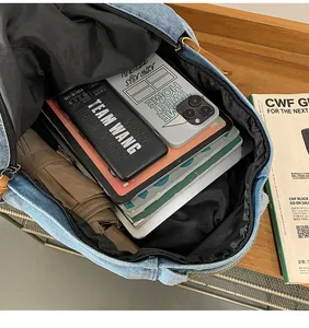 Detail view of denim backpack showing large interior storage for tablets and essentials