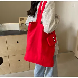 Sac fourre-tout en toile rouge avec breloque œil sur modèle montrant la taille et capacité