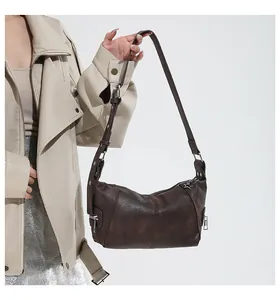 Close-up of retro brown shoulder bag featuring visible stitching and star charm detail