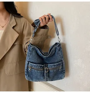 Detail of vintage washed denim tote bag with metal zippers and adjustable strap
