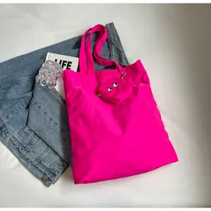 Détail du sac cabas en nylon rose néon avec un mini porte-monnaie motif yeux de dessin animé
