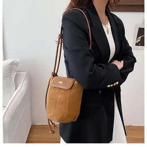 Close-up of brown suede and leather bucket bag featuring a sleek metal trim bar detail