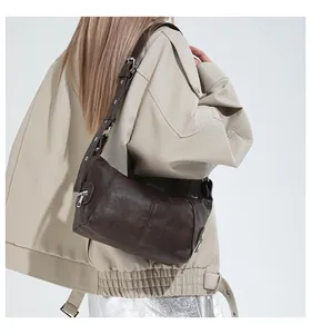 Close-up of retro brown textured leather shoulder bag with adjustable silver hardware strap