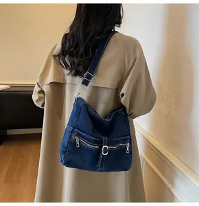 Detail of vintage denim crossbody bag featuring silver buckles and adjustable strap