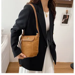 Detail of brown suede bucket bag with dark leather trim and vertical double stitching