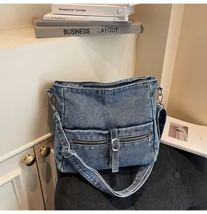 Close-up of vintage blue denim crossbody bag with dual front zippers and metal buckles
