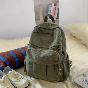 Detailansicht des grünen Cord-Rucksacks mit geripptem Stoff und vorderer Reißverschlusstasche