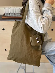 Sac fourre-tout en nylon vert olive avec pochette œil brodée porté par un mannequin