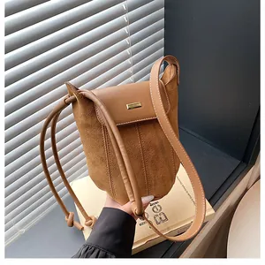 Detail of caramel suede and smooth leather patchwork bag with golden metal buckle