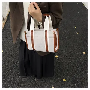 Detailaufnahme der Canvas-Tasche mit braunem Kunstlederbesatz und Nieten auf der Straße