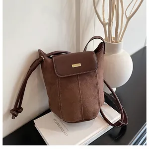 Detailed shot of dark brown bucket bag with contrast leather textures and gold hardware