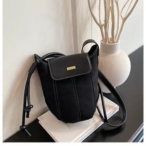 Detail of black bucket bag with leather patchwork, stitching, and gold metal hardware