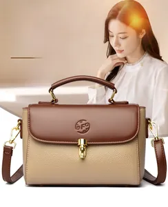 Detail of minimalist leather baguette bag featuring contrast panel and gold twist lock clasp