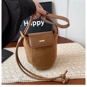 Detail of brown suede shoulder bag with gold metal buckle and elegant knot decoration