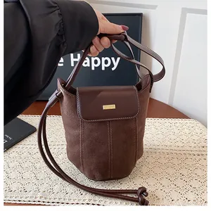 Close-up of brown bucket bag with mixed textures, suede panel and gold buckle detail