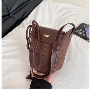 Detail of coffee brown bucket bag showing contrast stitching and gold metal buckle