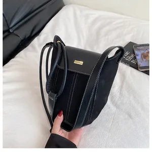Detail of black suede and leather patchwork bag with white contrast stitching and gold buckle