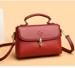 Detail of red pebbled leather handbag with gold metal lock and embossed F logo