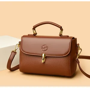 Detail view of brown leather bag with embossed letter F logo and golden clasp lock