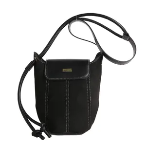 Black bucket shoulder bag in suede and leather with contrast stitching and gold buckle