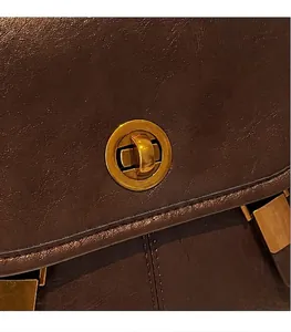 Close-up of vintage dark brown leather texture with a gold circular twist lock fastener