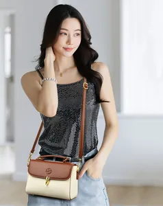 Detail of two-tone cream and brown leather handbag with gold twist lock and logo detail