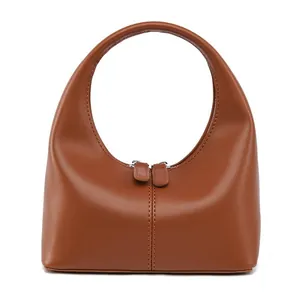 Detail einer braunen matten Lederhandtasche mit gebogener Silhouette und Doppelreißverschluss