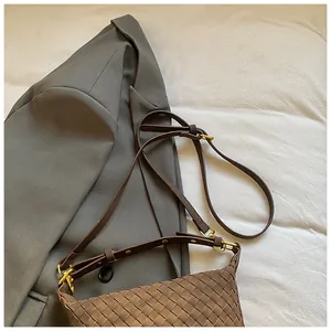 Close-up of brown woven leather texture and gold hardware on minimalist shoulder bag