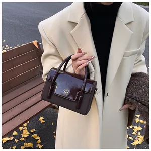 Detailed view of bicolor leather square bag with glossy patent finish and logo lettering