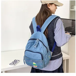 Vue détaillée du mini sac à dos en denim avec écusson arc-en-ciel sur un mannequin
