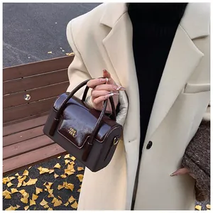 Detail of a vintage dark brown leather crossbody bag featuring gold hardware on a bench