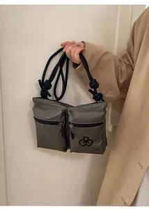 Detail view of dark grey nylon crossbody bag featuring double front zippers and rope strap