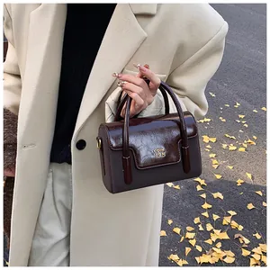 Close-up of retro brown square bag featuring glossy textured flap and gold COIH 2DN logo