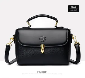 Detail of black lychee grain leather handbag with gold metal lock and embossed logo
