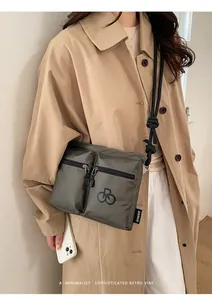Detail of waterproof olive green nylon crossbody bag with dual zippered pockets and strap