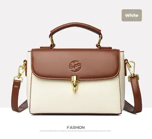 Detailed view of cream leather bag with brown flap and golden metallic lock clasp