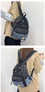 Détails rapprochés d'un mini sac à dos en denim délavé avec broderie arc-en-ciel et poches multiples