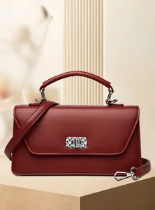 Detalle del cierre metálico plateado y textura de cuero rojo oscuro en el bolso de mano