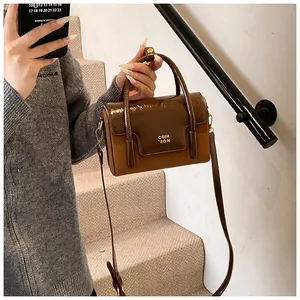 Detail view of structured brown panelled crossbody bag with golden COIH 2DN branding
