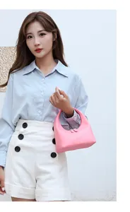 Rosafarbene Hobo-Tasche aus Leder mit Griff und Halbmondform, von einem Model getragen